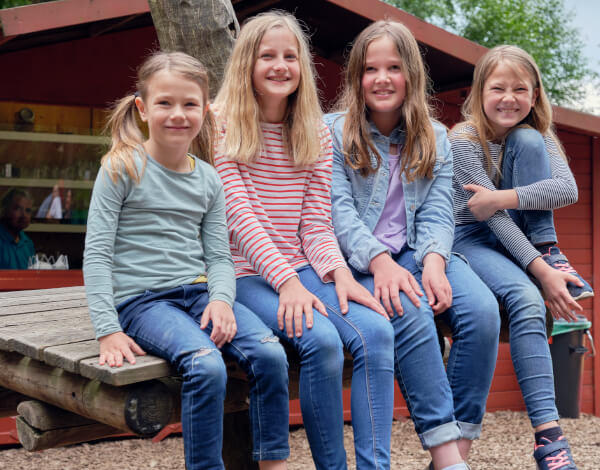 Vier Mdchen sitzen auf einem Tisch und schauen lachend in die Kamera